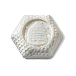 Hexagonal bar of white soap featuring an embossed honeycomb and beehive design.