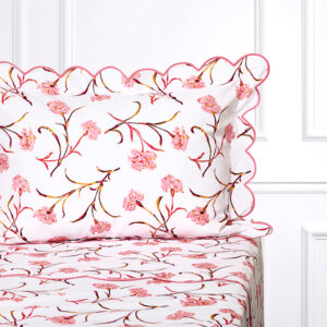 White bedding with pink and burgundy carnation floral patterns and scalloped edges.