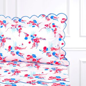 Floral bed linens with red, blue, and pink patterns, featuring a scalloped pillow edge.