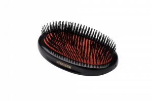 A small, dark ruby hairbrush with extra bristles, featuring a black handle and logo.