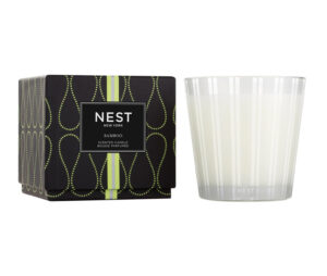 A bamboo-scented candle next to its decorative black box with green accents.