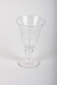 Clear glass goblet with a textured surface and a round base, standing upright on a white background.