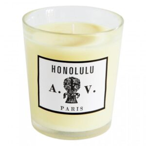 A glass candle with a label reading "HONOLULU A.V. PARIS" and a light yellow wax interior.