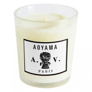 White candle in a clear glass holder with a label reading "Aoyama A.V. Paris.
