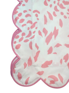 Pink and white scalloped shams with abstract patterns in soft hues.