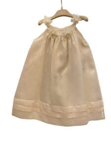 Silk dress with floral embellishments and layered hem, displayed on a hanger.