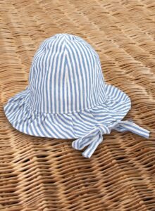 A blue and white striped sun hat rests on a woven surface.