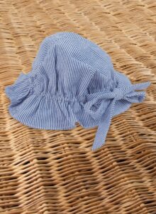 A blue and white striped sun hat rests on a woven surface.