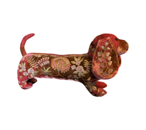 A pink silk velvet dachshund with floral embroidery stands upright.
