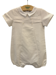 White pique romper with short sleeves, collar, and button details, hanging on a wooden hanger.