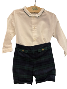 White collared shirt with buttons paired with black watch plaid shorts featuring decorative buttons.
