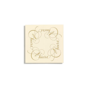 A cream coaster with elegant gold script spelling "Cheers" in a circular pattern.