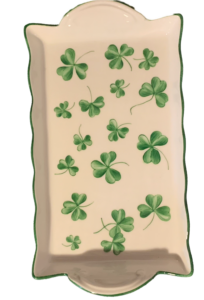 A rectangular tray decorated with various green clovers on a white background.