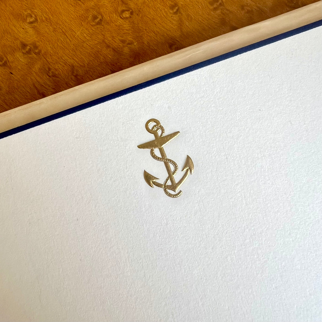 A gold anchor emblem on textured white paper with a blue border.