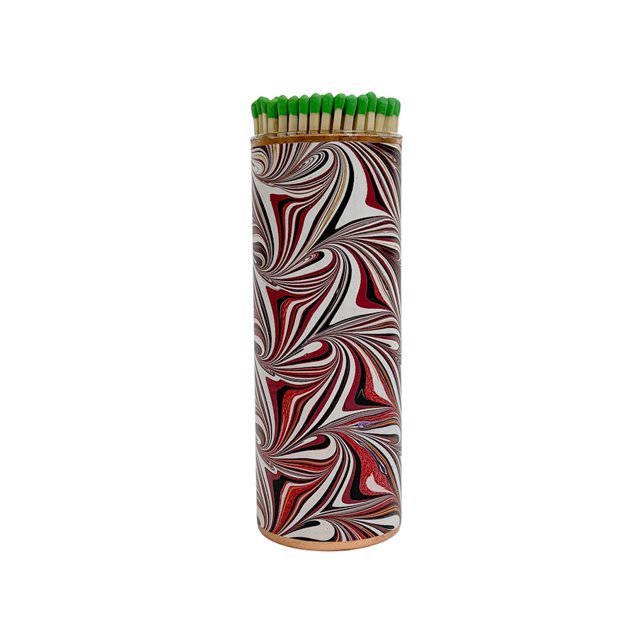 A decorative matchbox with green-tipped matches, featuring a swirling red and black design.